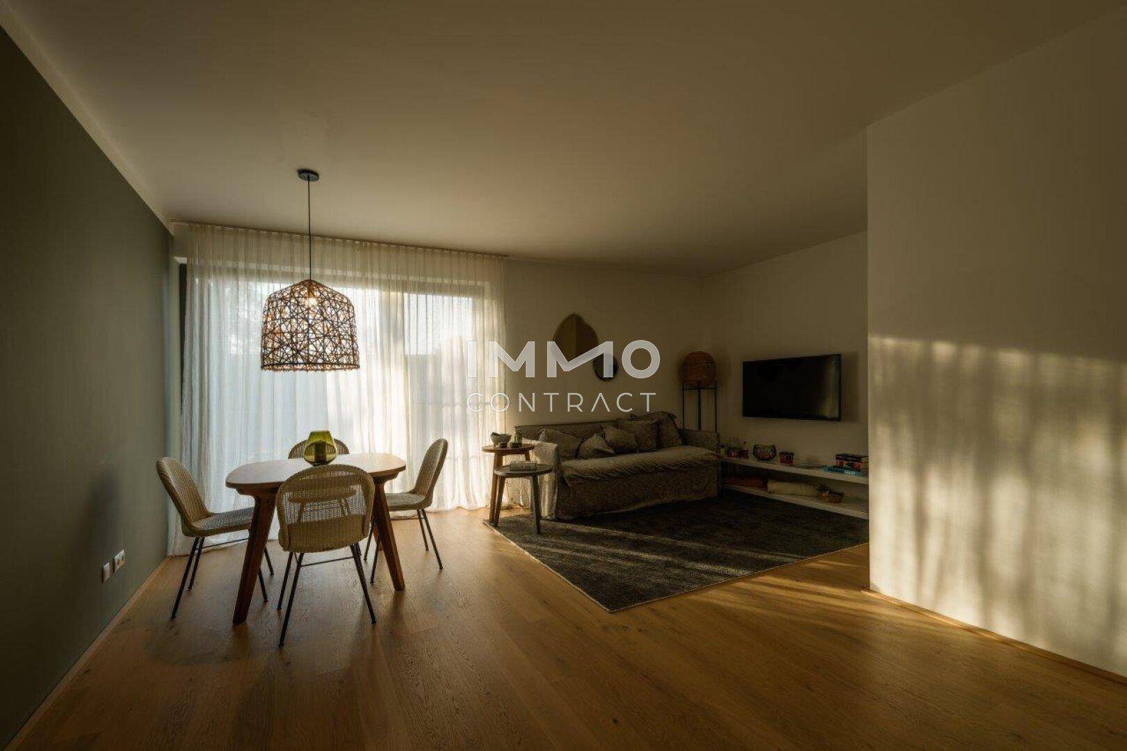Gemütlicher Wohn-Essbereich mit Holzboden, Esstisch und Sofa, hell durch große Fenster.