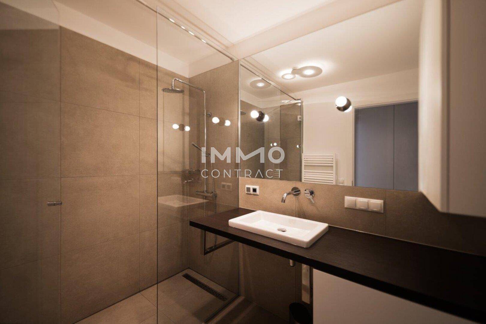 Modernes Badezimmer mit begehbarer Dusche, großem Spiegel und beheiztem Handtuchhalter.