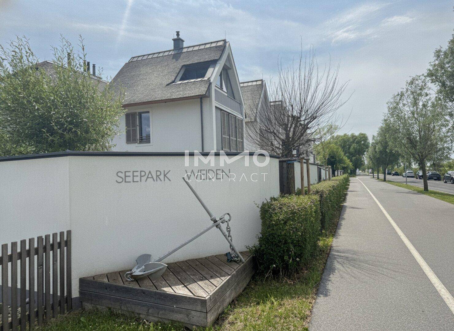 Eingangsbereich der Wohnanlage Seepark Weiden mit moderner Architektur und Reetdächern.