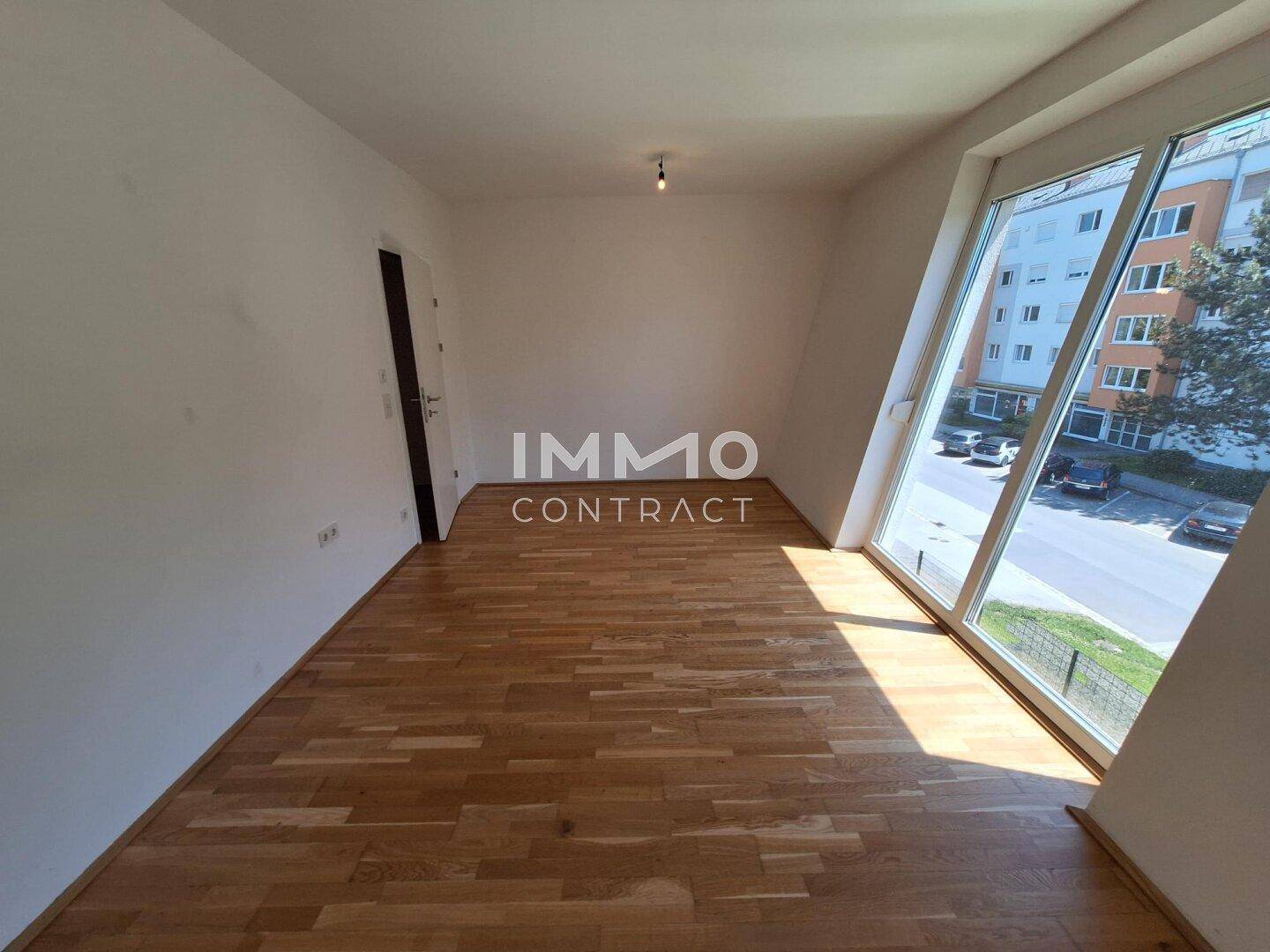 Helles Zimmer mit Holzboden und schrägen Fenstern, die viel Licht hereinlassen.