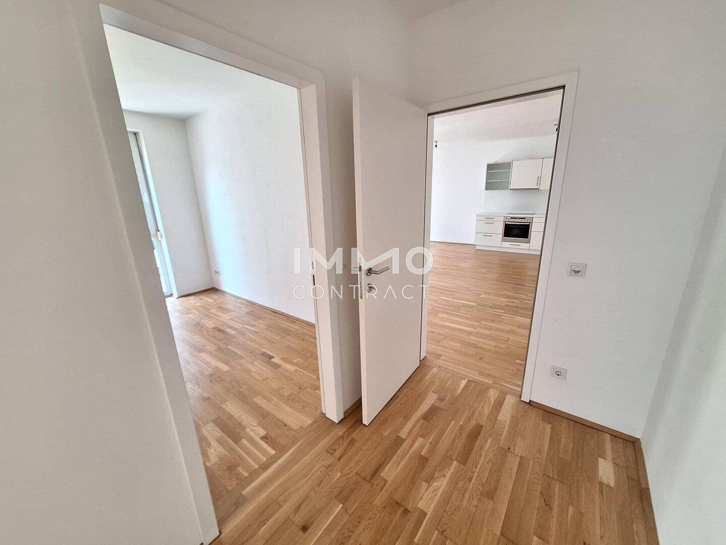 Heller Flur mit Holzboden und Türen zu angrenzenden Räumen.