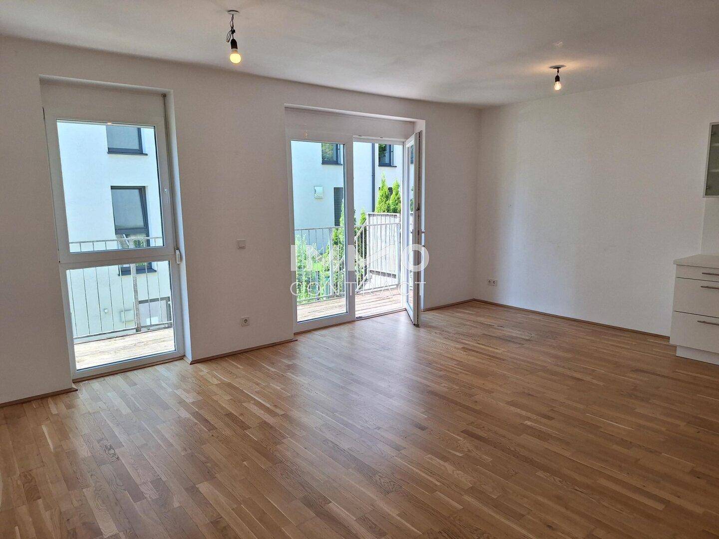 Helles Wohnzimmer mit Holzboden und Zugang zu einem Balkon, bereit zur Einrichtung.