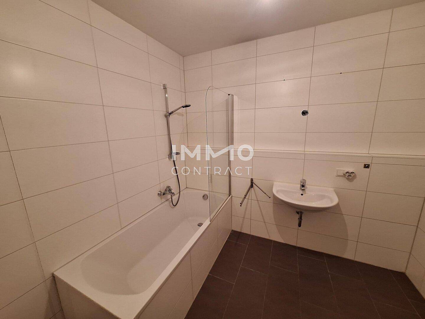 Modernes Badezimmer mit Badewanne, Dusche und Waschbecken, hell gefliest.