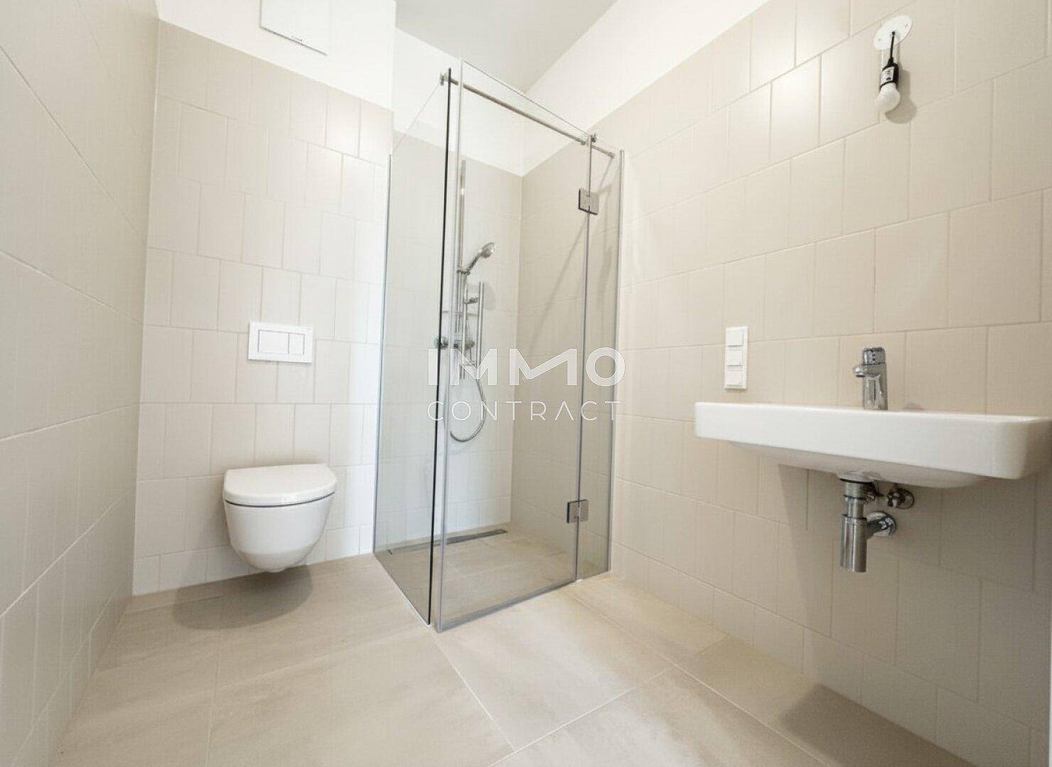 Modernes Badezimmer mit ebenerdiger Dusche, wandhängendem WC und hellem Fliesenboden.
