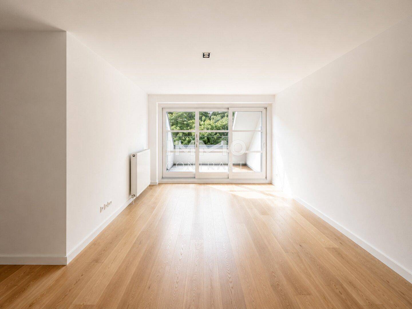 Lichtdurchfluteter Raum mit Parkettboden und großem Schiebetürfenster zum Balkon.