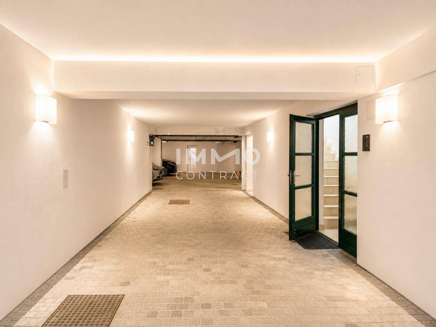 Tiefgarage mit gepflastertem Boden, moderner Beleuchtung und Zugang zum Treppenhaus.