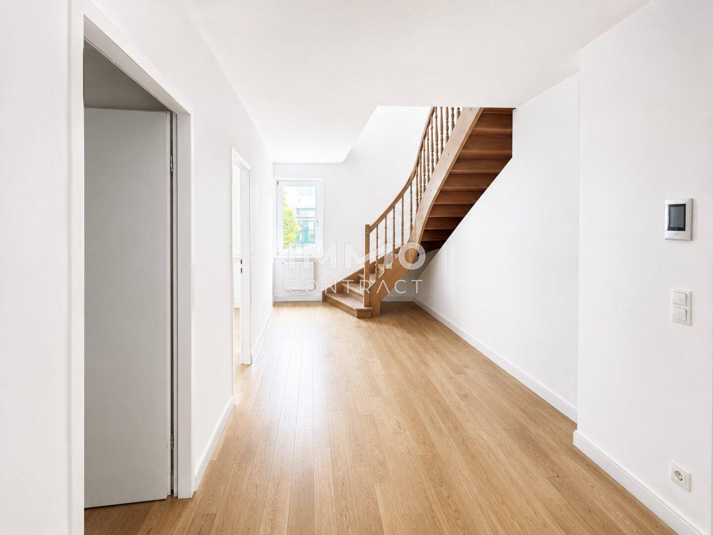 Heller Flur mit Parkettboden und einer eleganten Holztreppe, die in die oberen Stockwerke führt.