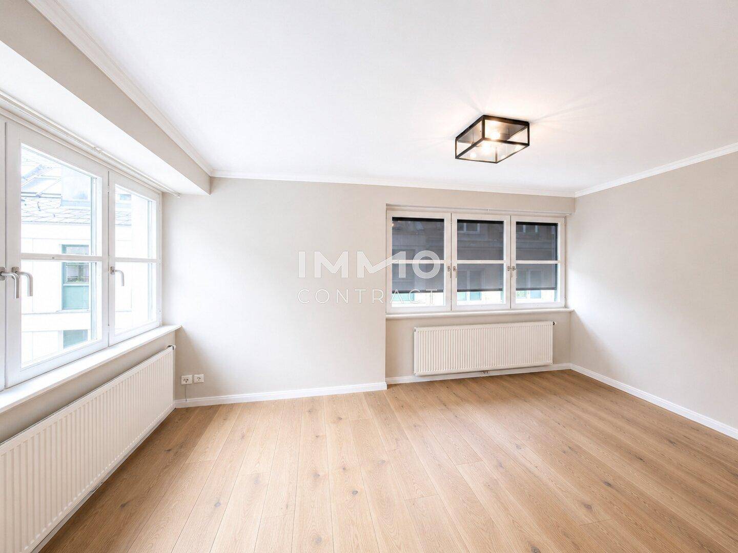 Geräumiges Schlafzimmer mit hellem Parkettboden und großen Fenstern, viel Tageslicht.