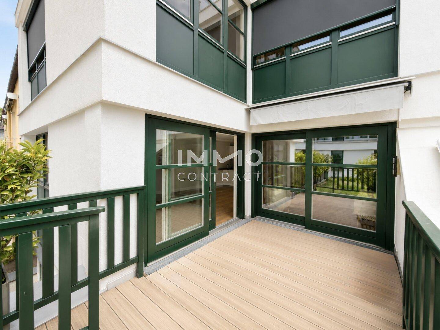 Heller Balkon mit Holzboden und Blick auf die Umgebung, zugänglich durch große Glastüren.
