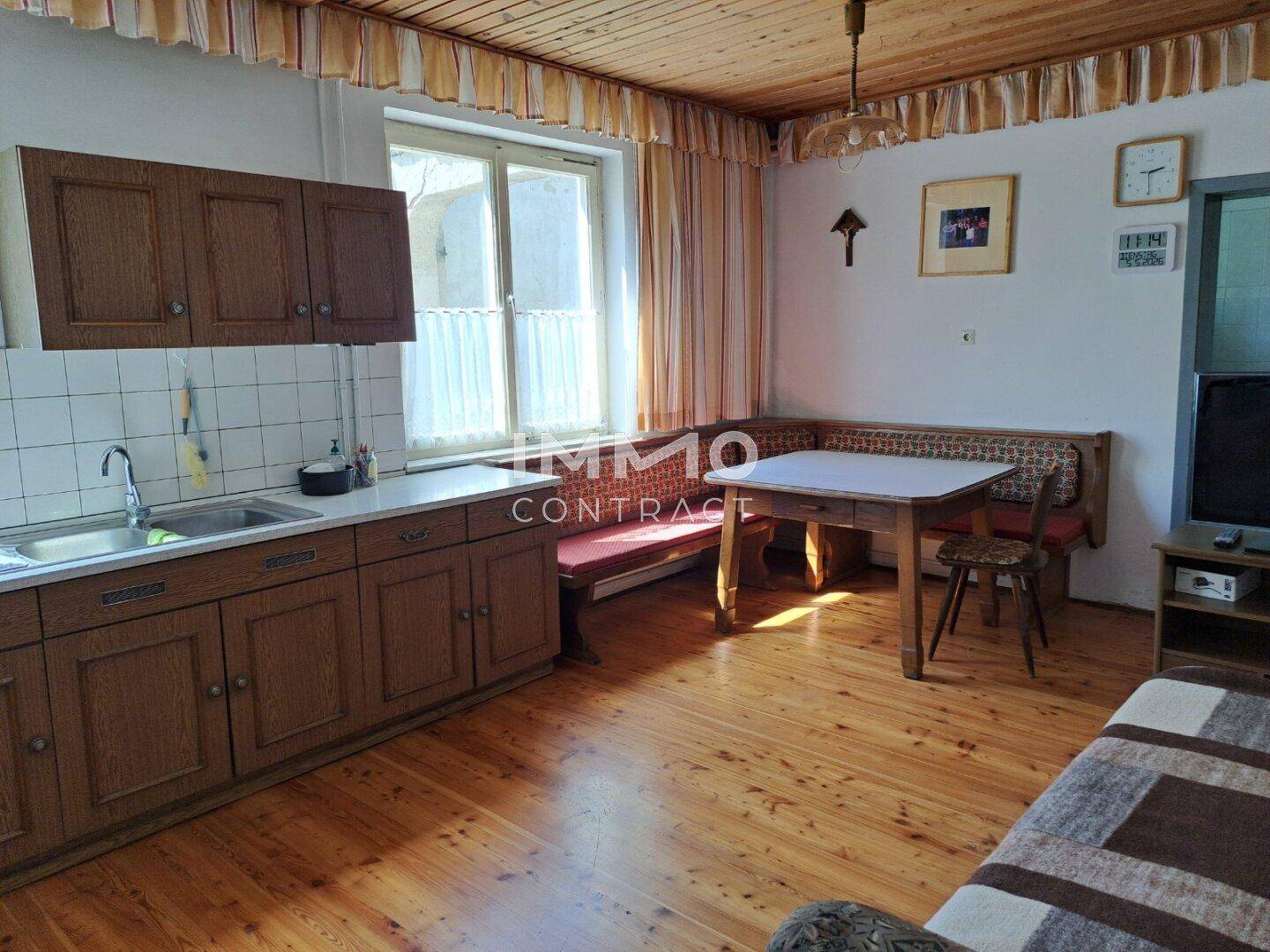 Gemütliche Wohnküche mit Holzboden, Einbaubank und Blick auf den Garten.