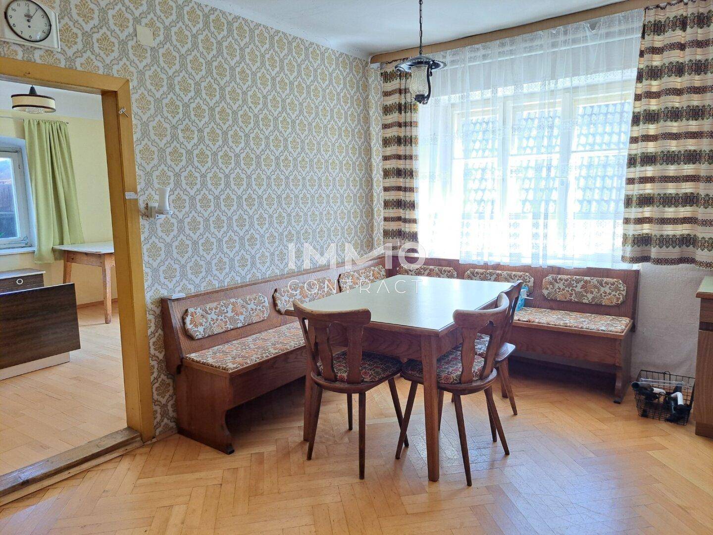 Essbereich mit Holztisch, Eckbank und gemusterten Tapeten in traditionellem Stil.