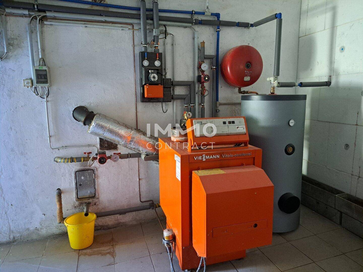 Heizungsraum mit Ölheizung, Warmwasserspeicher und sichtbaren Rohrleitungen.