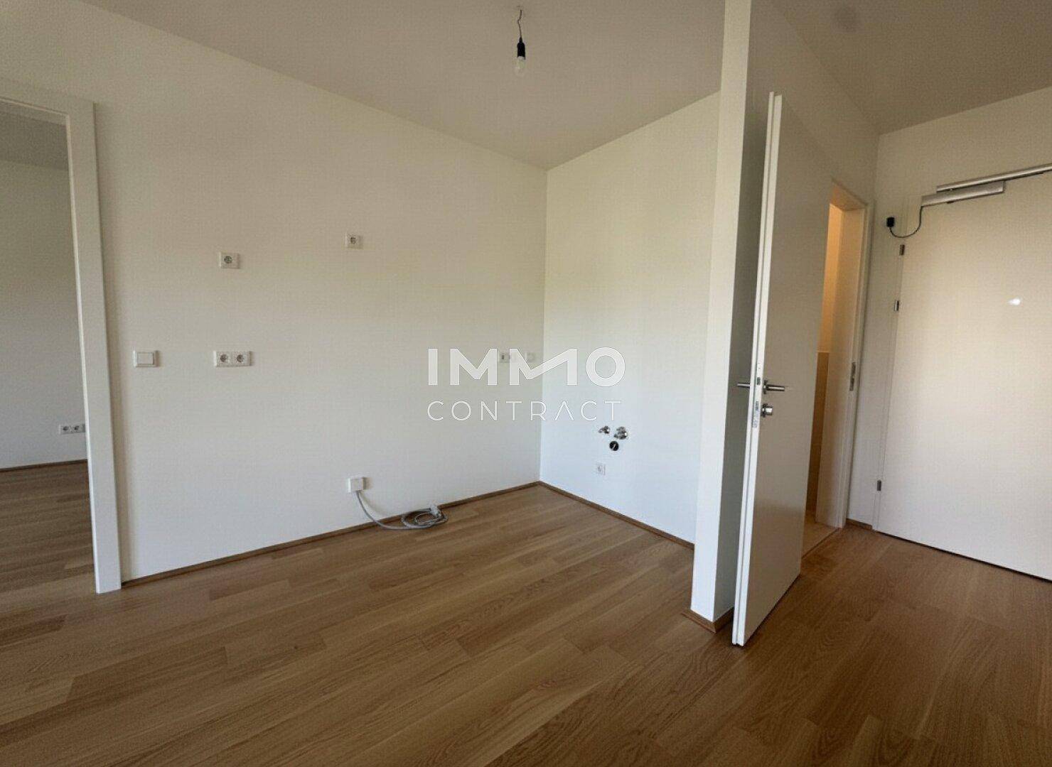 Leeres Zimmer mit Holzboden und weiß gestrichenen Wänden, bereit zur Einrichtung.