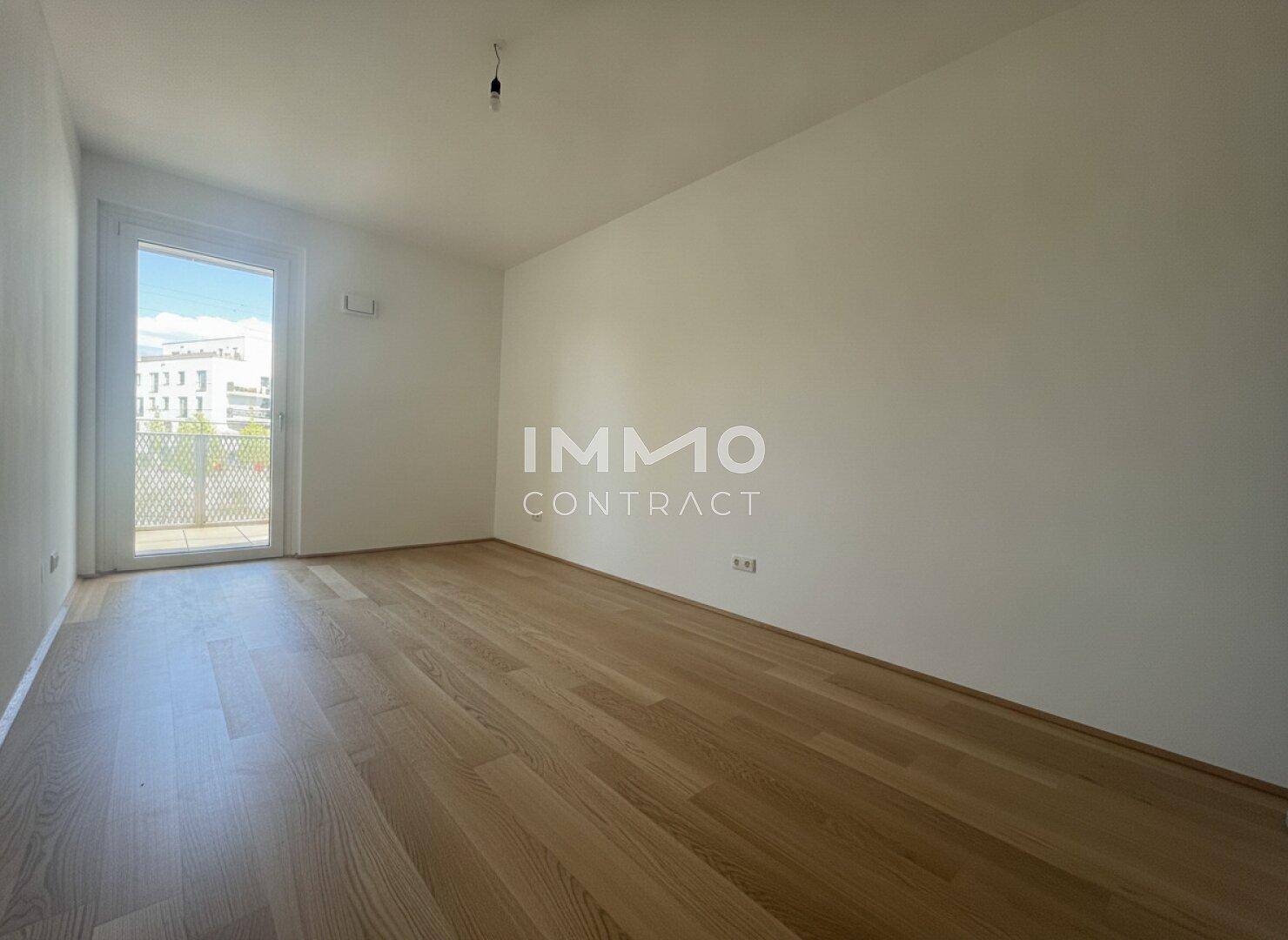 Helles Zimmer mit Holzboden und Zugang zu einem französischen Balkon.