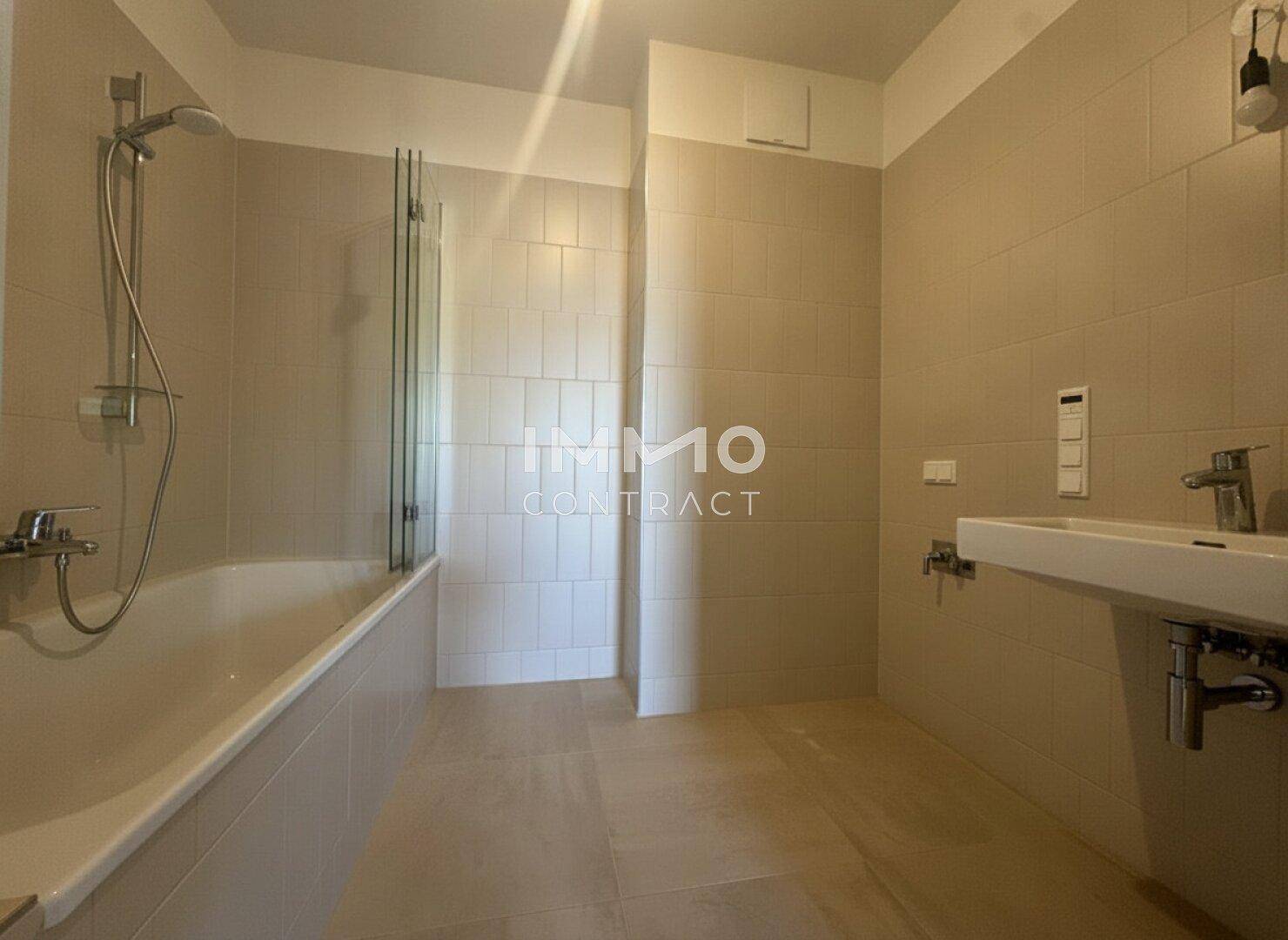 Helles Badezimmer mit Badewanne, Duschabtrennung und modernem Waschbecken.