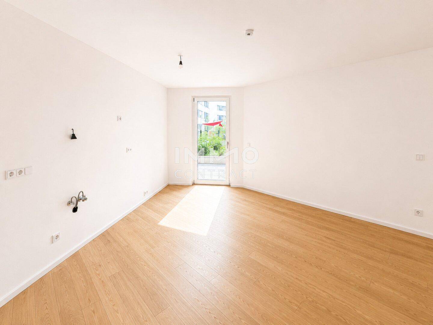 Heller Raum mit Holzboden und direktem Zugang zu einem privaten Garten oder einer Terrasse.