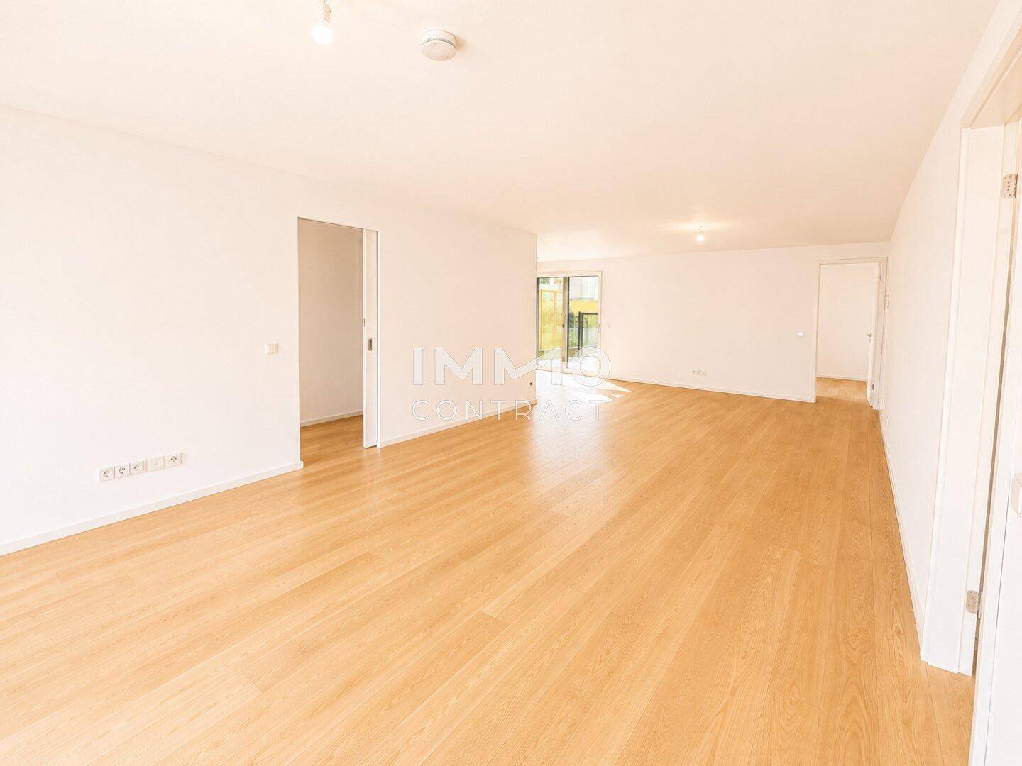 Weitläufiger, heller Wohnbereich mit Holzboden und viel Tageslicht, bereit zur individuellen Gestaltung.