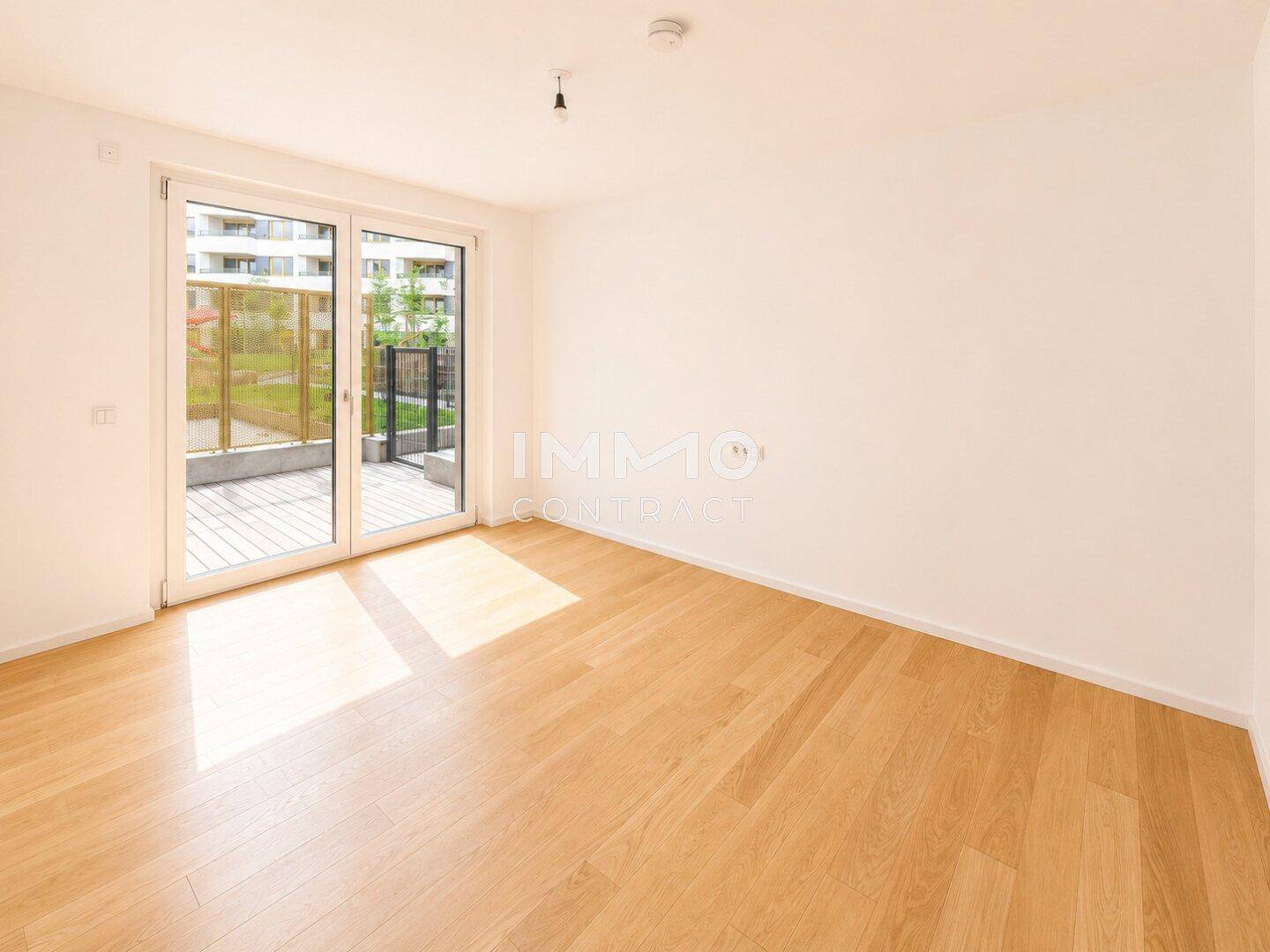 Lichtdurchflutetes Zimmer mit Holzboden und direktem Zugang zur Terrasse, ideal für Entspannung.