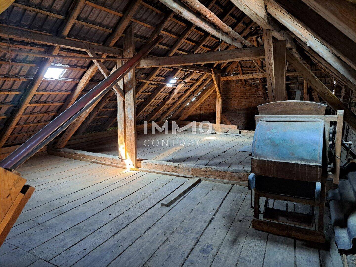 Geräumiger Dachboden mit Holzbalken, Dielenboden und Dachfenster.