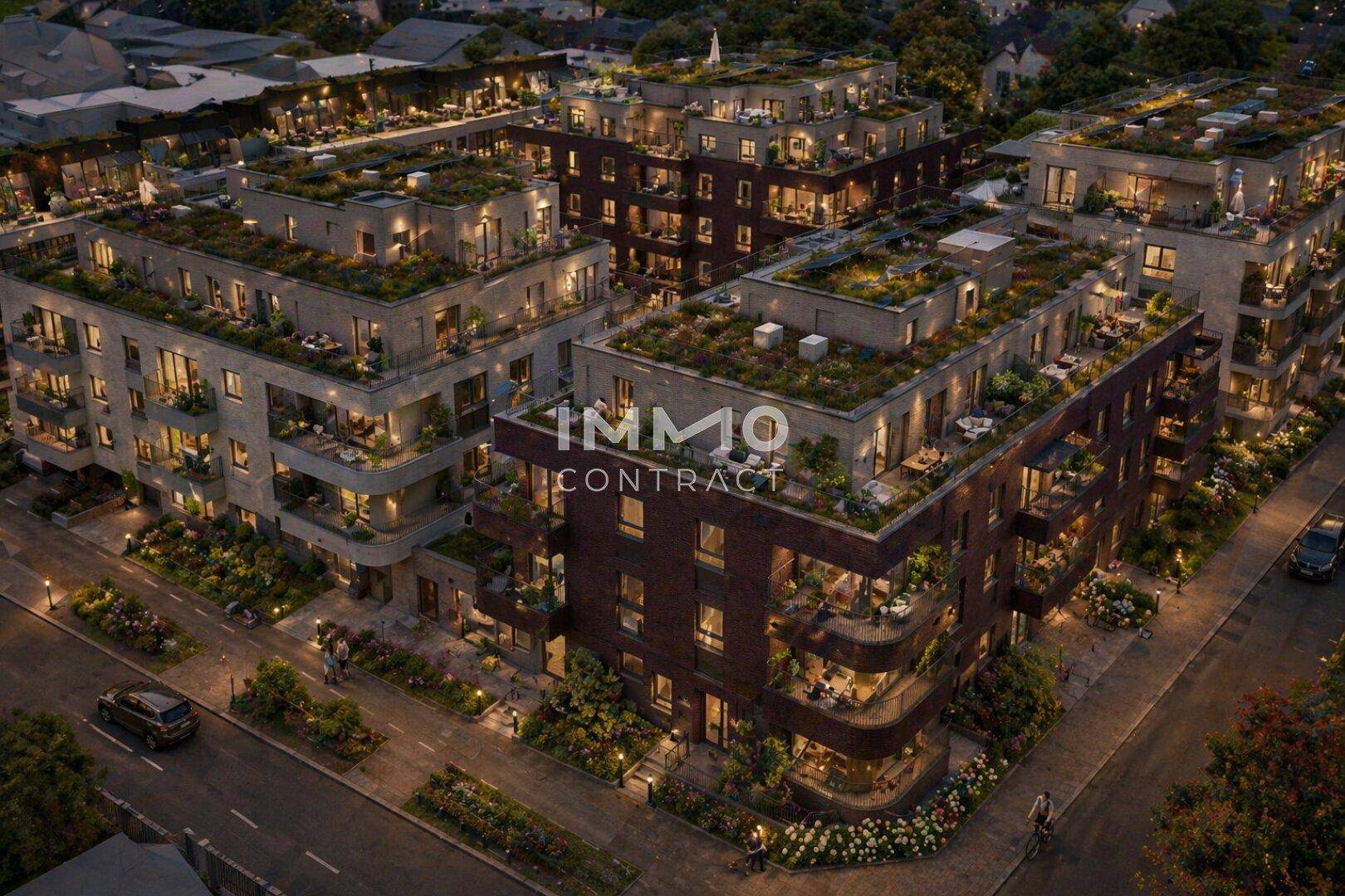 Nächtliche Luftaufnahme des modernen Wohnkomplexes mit beleuchteten Wohnungen und begrünten Dächern.