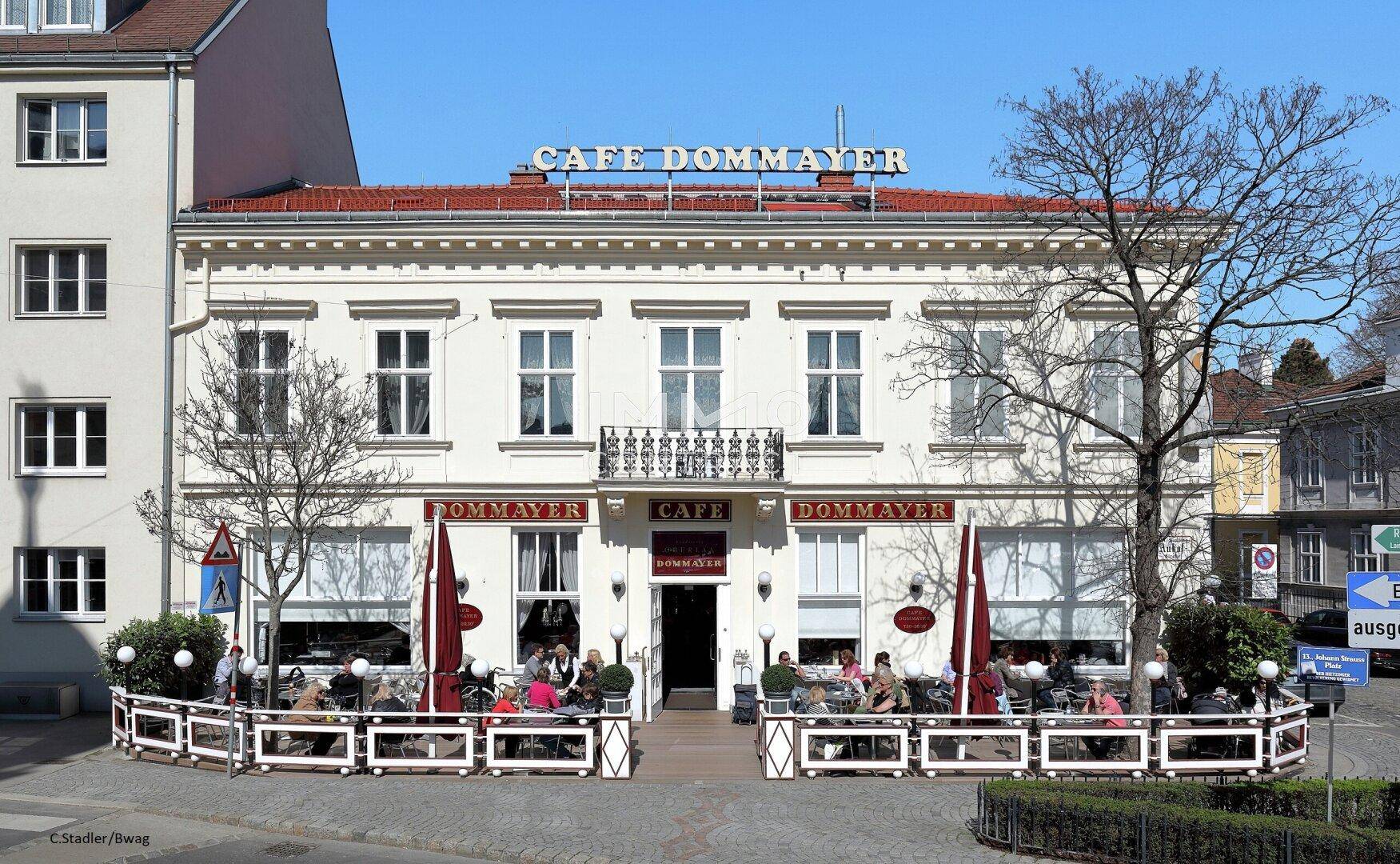 Historisches Café Dommayer mit traditioneller Fassade und belebter Außenterrasse in Wien.