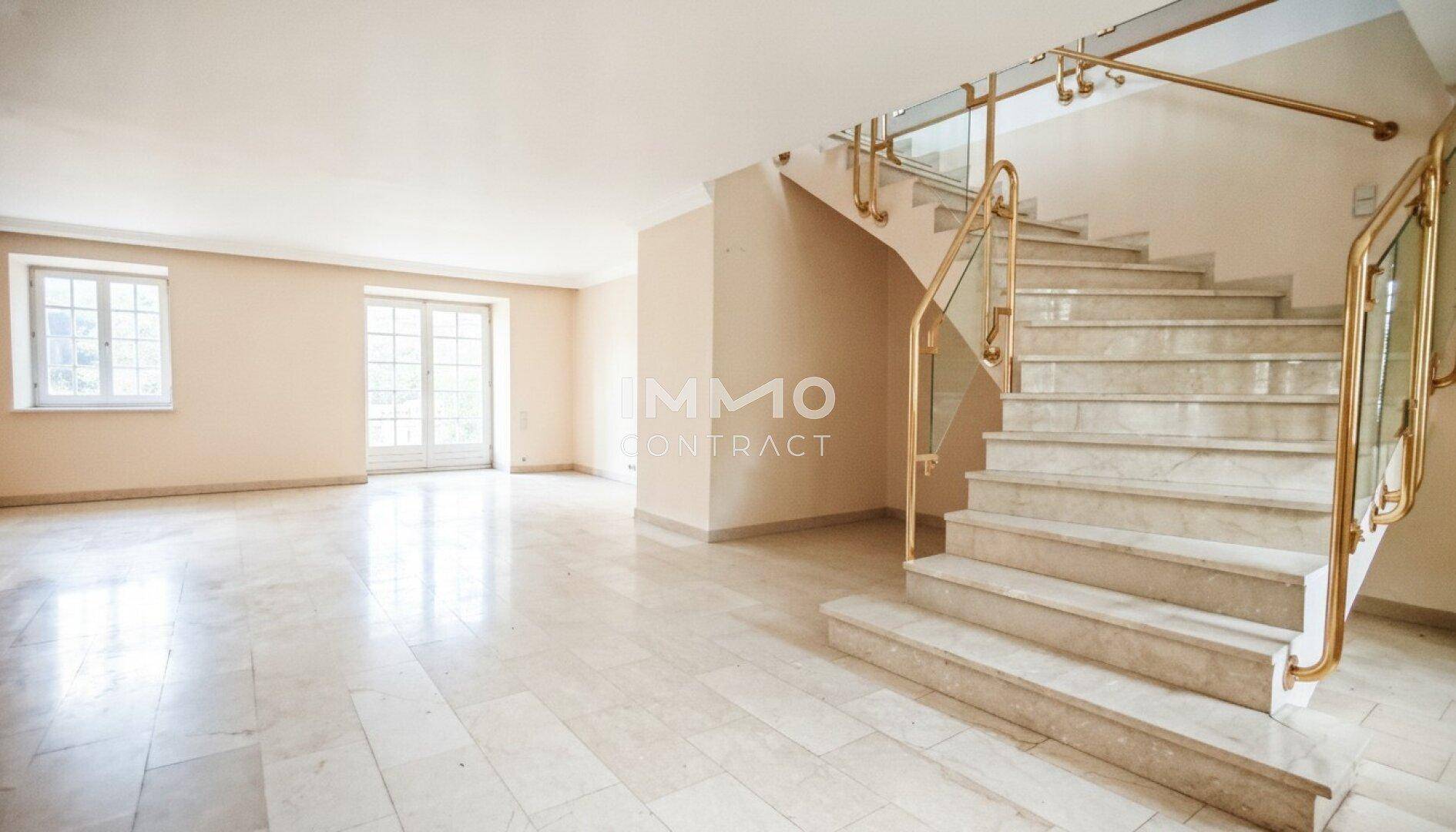 Geräumiger Eingangsbereich mit eleganter Marmortreppe und glänzendem Fliesenboden, der zum Obergeschoss führt.