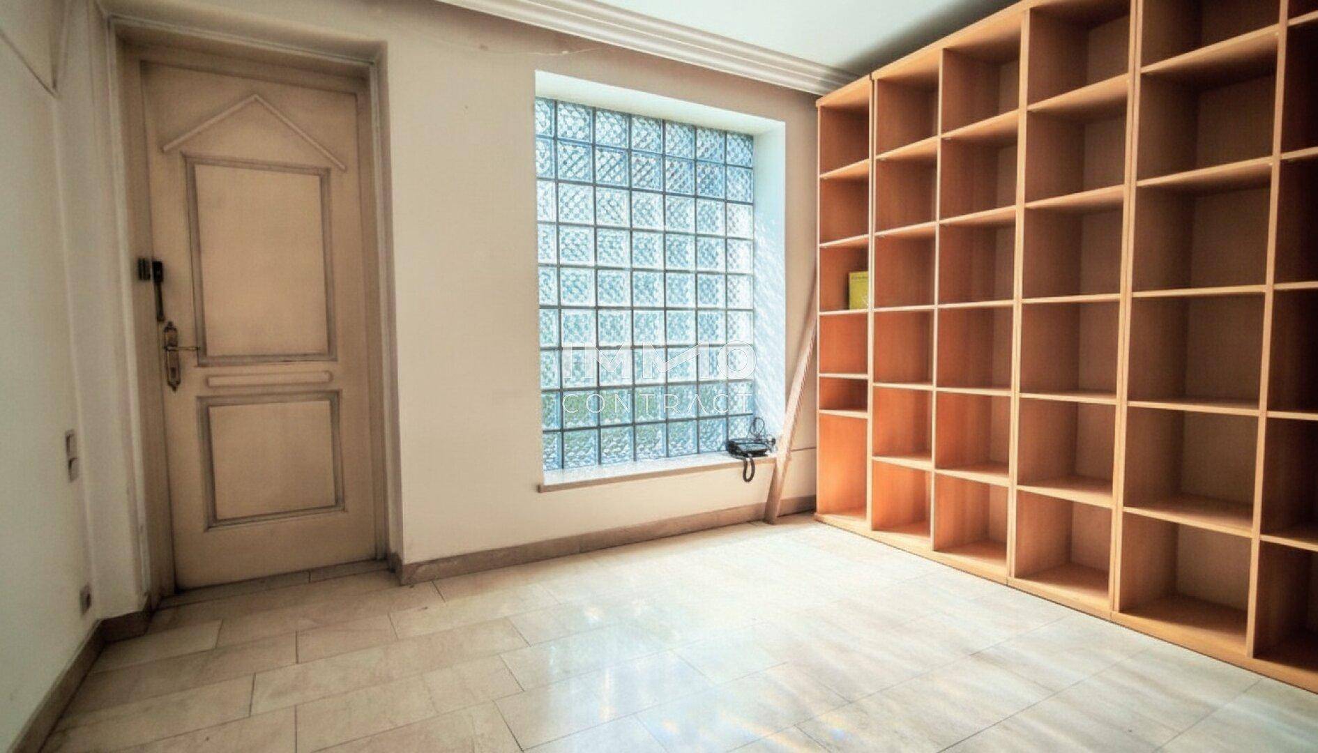 Raum mit großer Holzregalwand und Glasbausteinfenster, ideal für Lagerung oder Bibliothek.