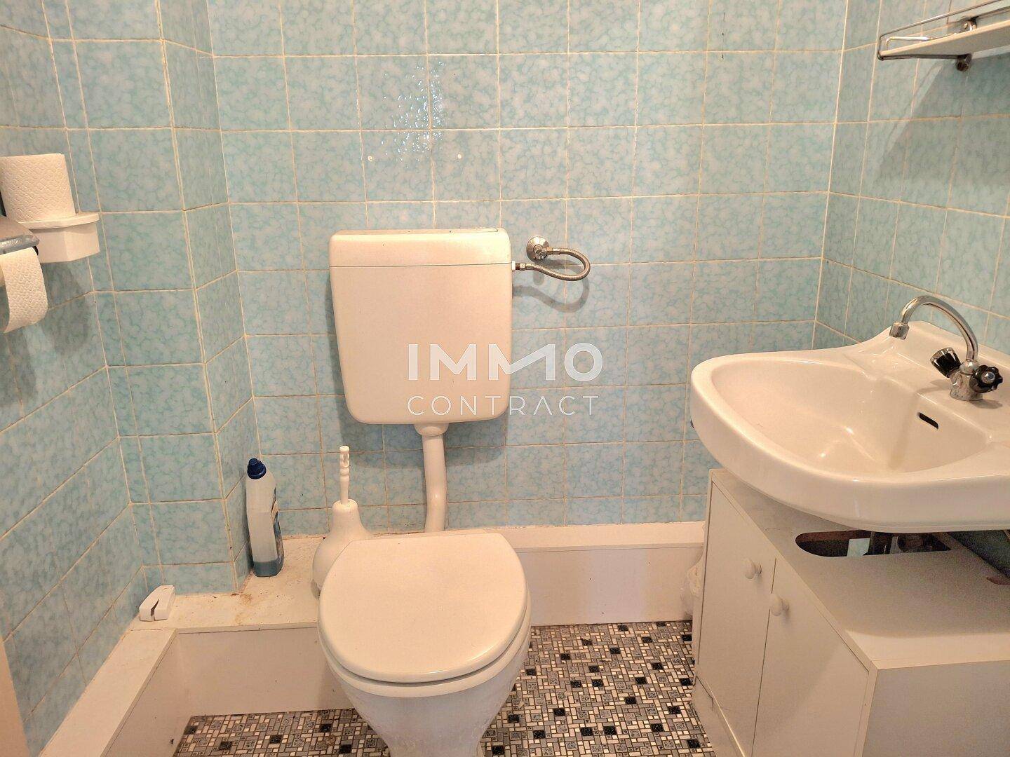 Toilette mit WC, Waschbecken und blauen Fliesen mit kariertem Boden, einfach und sauber.