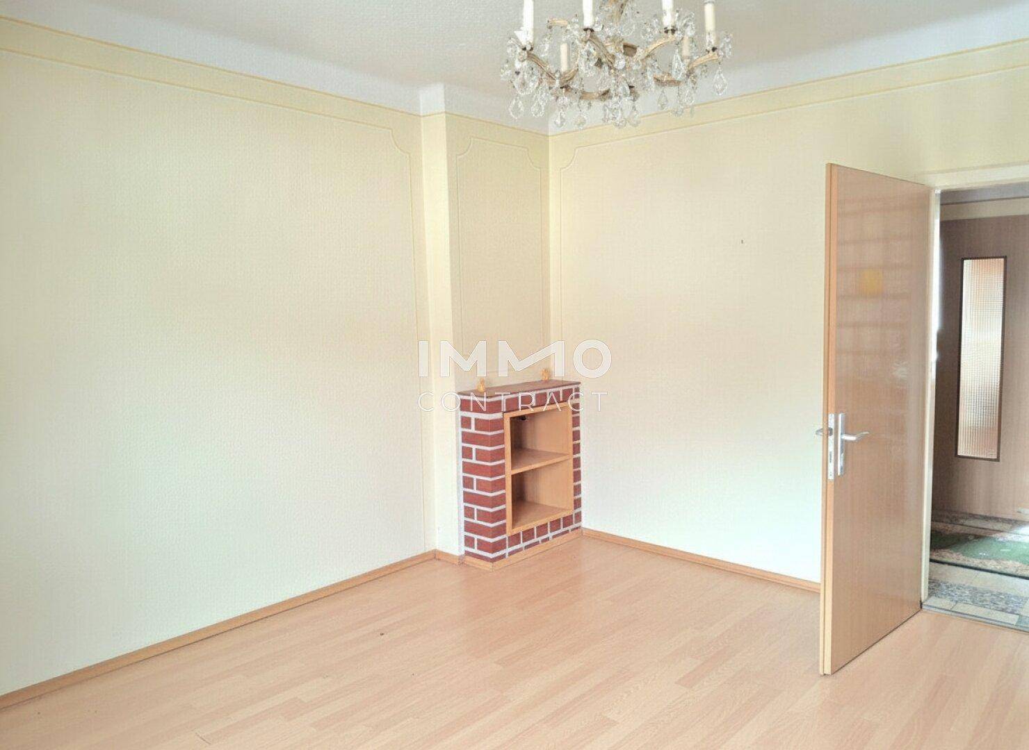 Wohnzimmer mit Laminatboden, einem dekorativen Kamin und Kronleuchter, bietet eine gemütliche Atmosphäre.