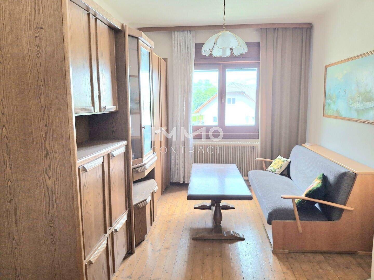 Wohnzimmer mit Holzdielenboden, Sofa und einem großen Schrank, bietet eine gemütliche Wohnatmosphäre.