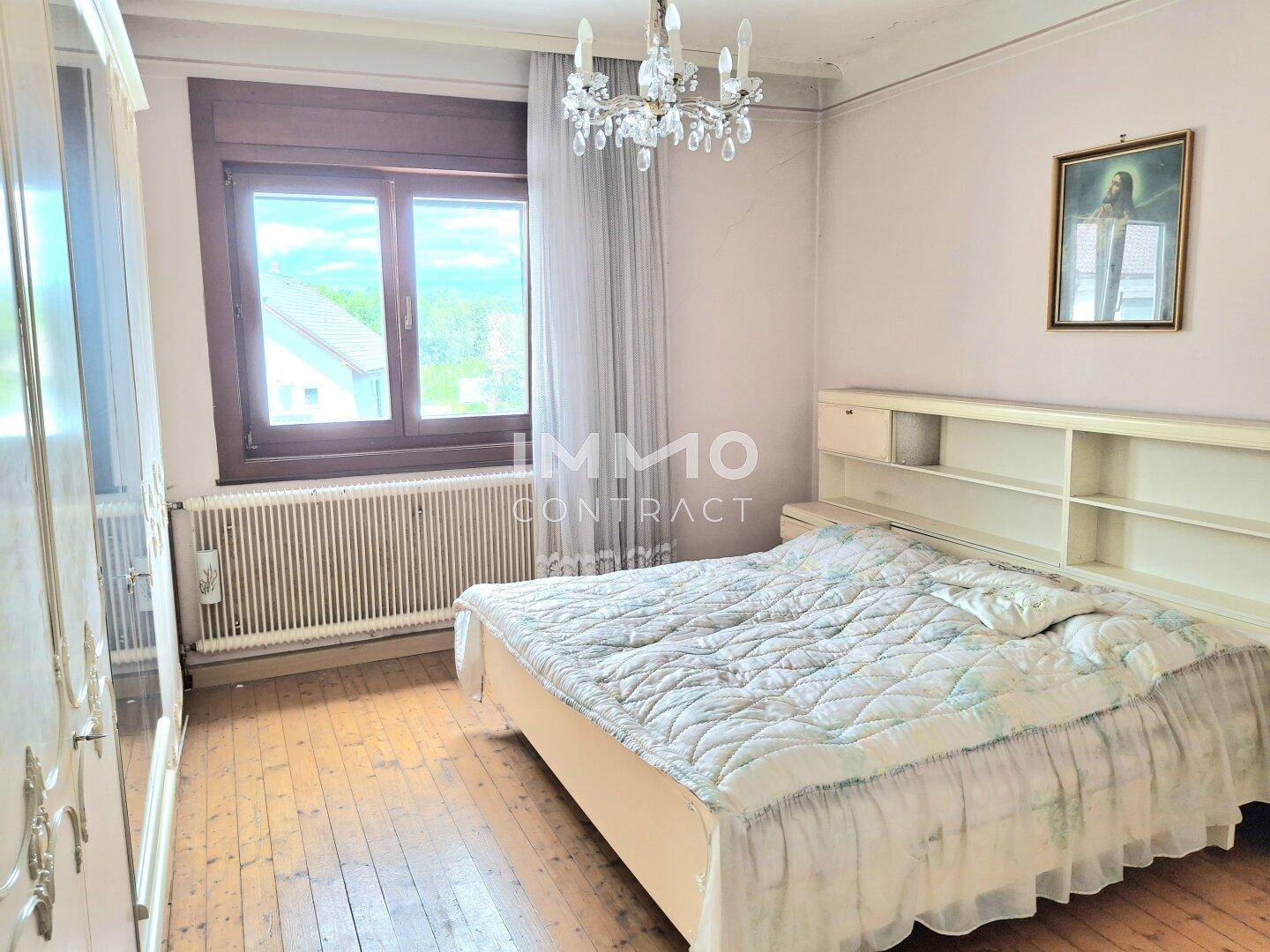 Schlafzimmer mit Holzdielenboden, Doppelbett und einem großen Kleiderschrank, hell und geräumig.