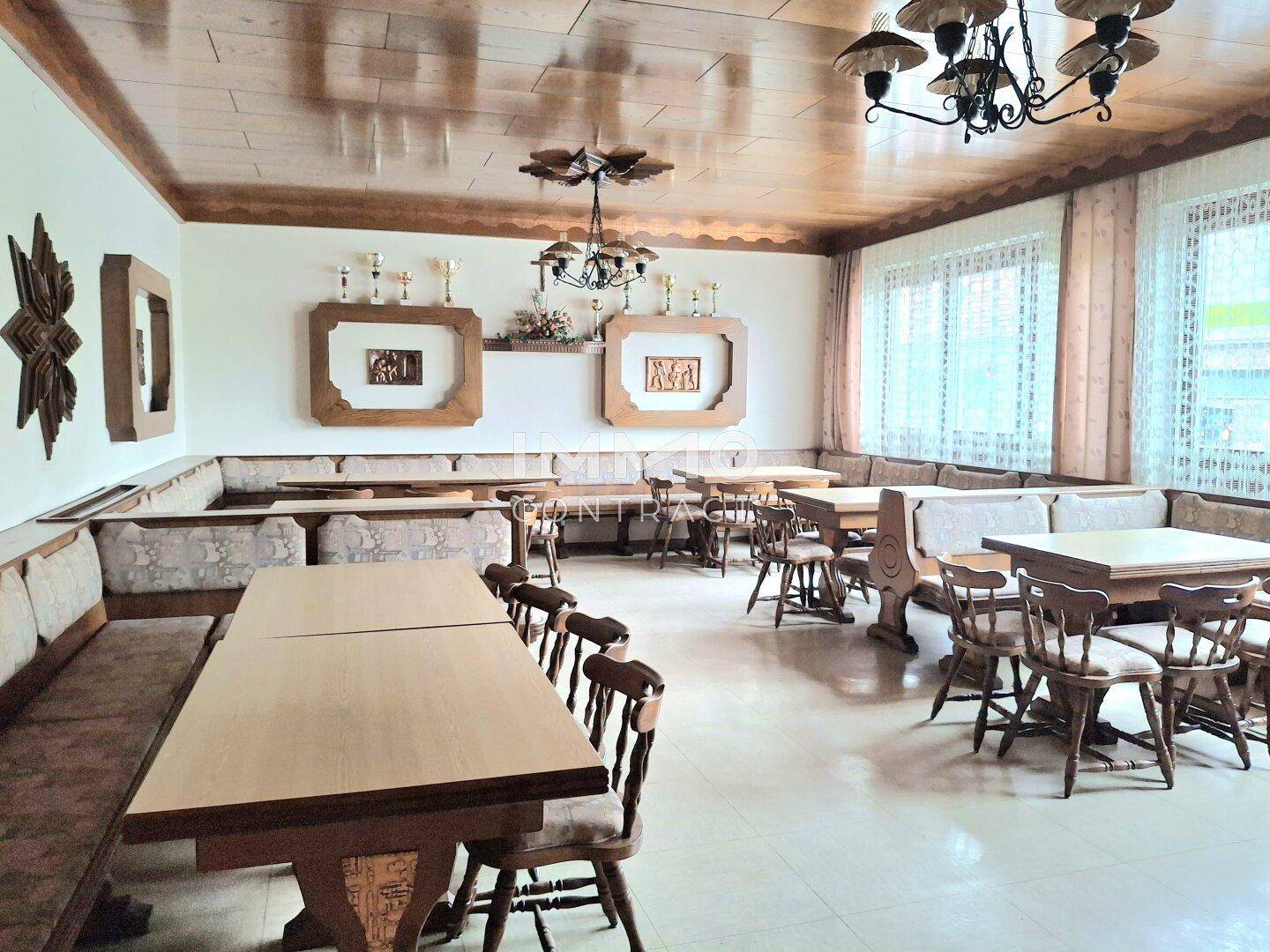 Gemütlicher Speisesaal mit Holzbalkendecke, Eckbänken und traditionellen Möbeln, hell und einladend.