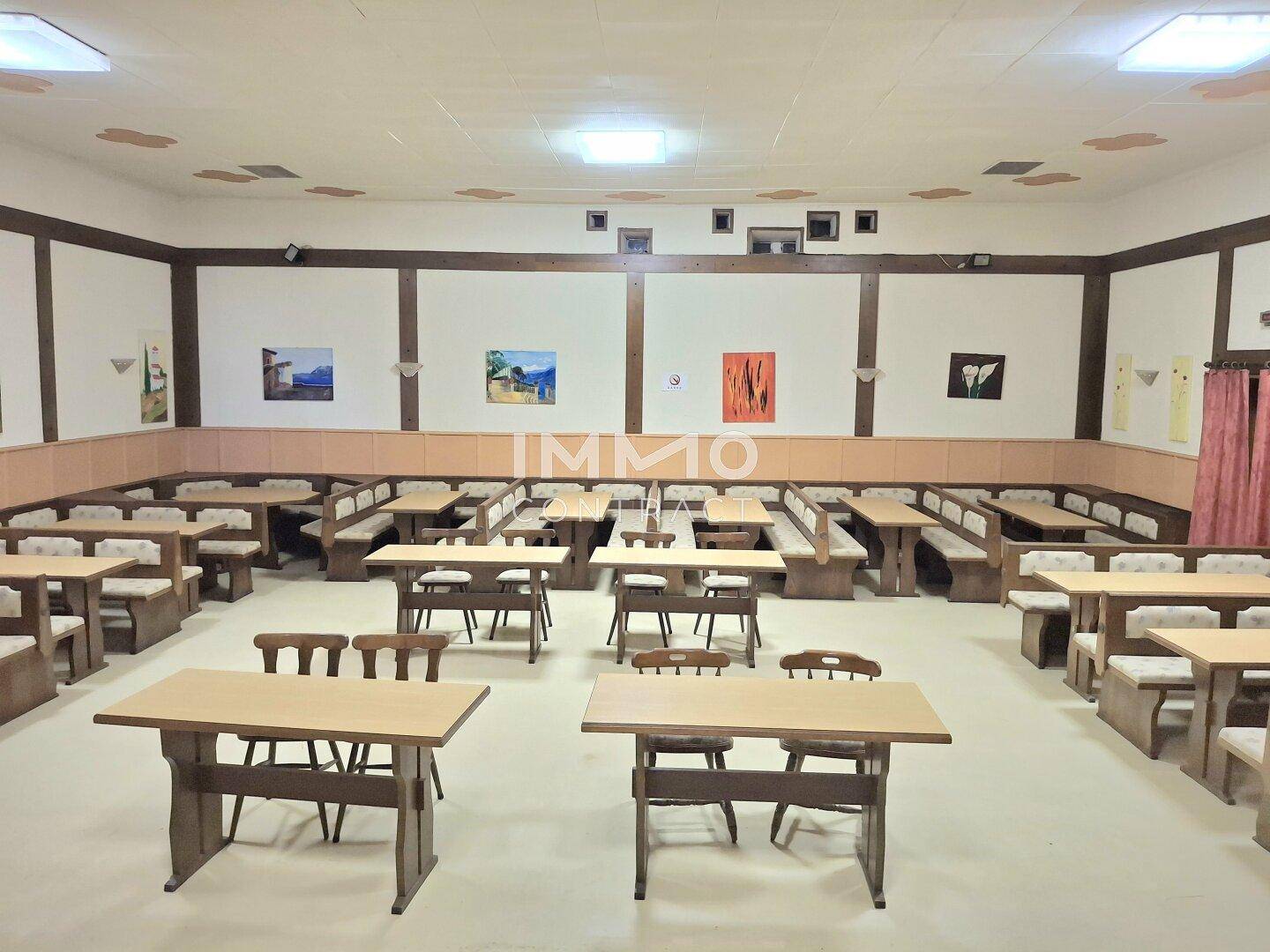 Großer Speisesaal mit vielen Holztischen und Bänken, ideal für Veranstaltungen und größere Gruppen.