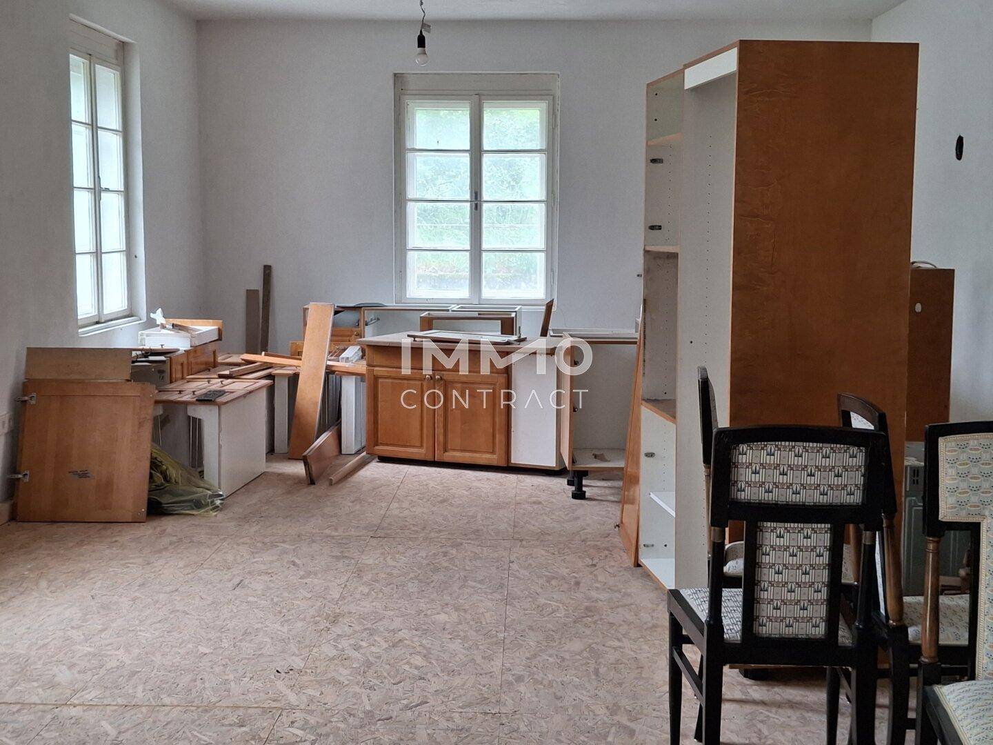 Raum in Renovierung mit vorbereiteten Küchenschränken und Fenstern, bereit für den Ausbau.