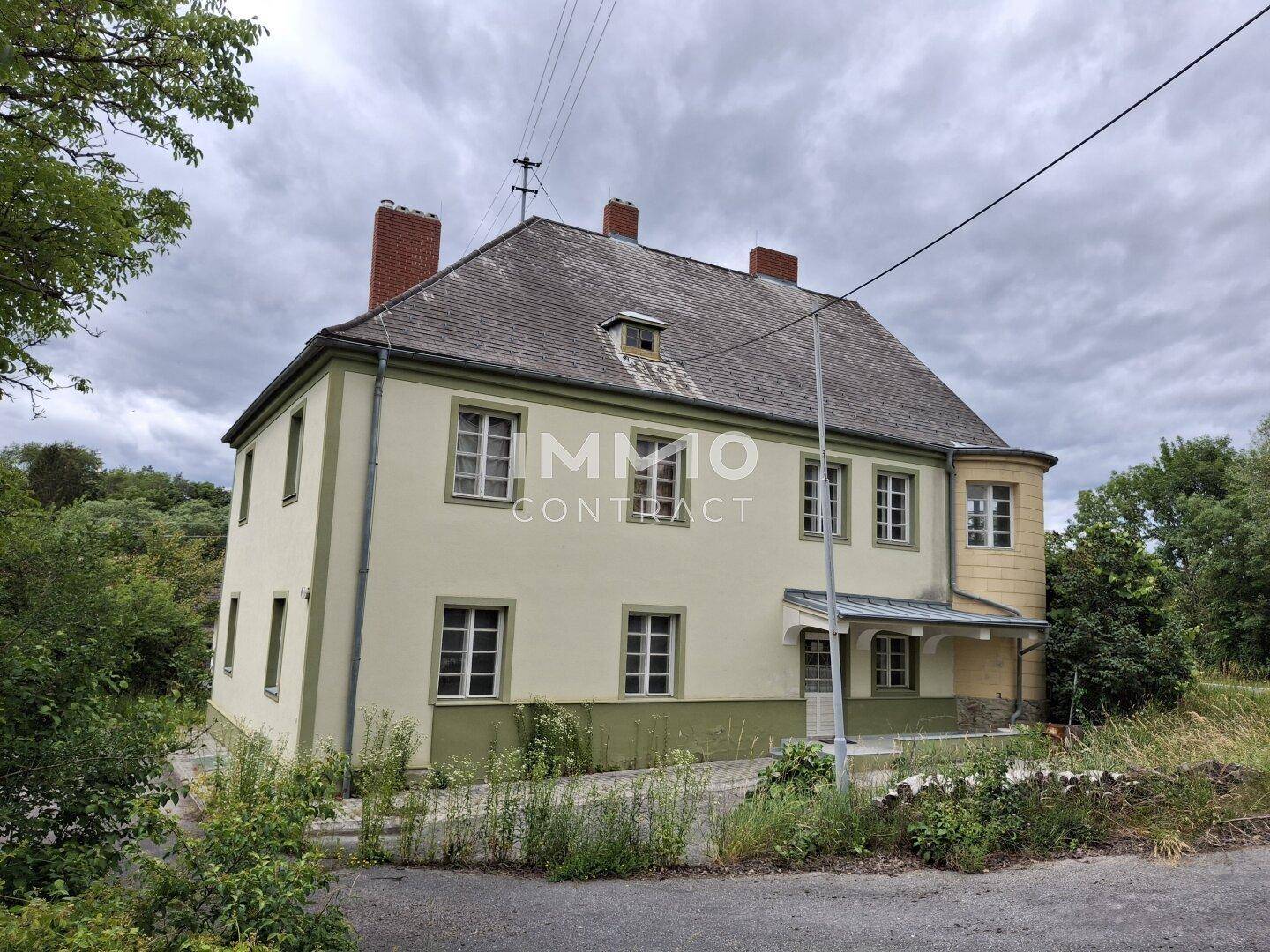 Weitläufige Ansicht des historischen Gebäudes mit seiner Fassade und der natürlichen Umgebung.