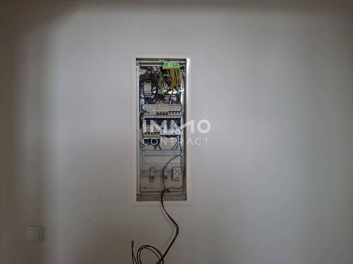 Offener Sicherungskasten an einer weißen Wand, zeigt die elektrische Installation des Hauses.