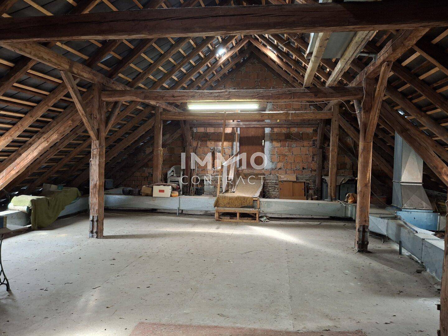 Geräumiger Dachboden mit sichtbaren Holzbalken und Ziegelwänden, bereit für einen möglichen Ausbau.