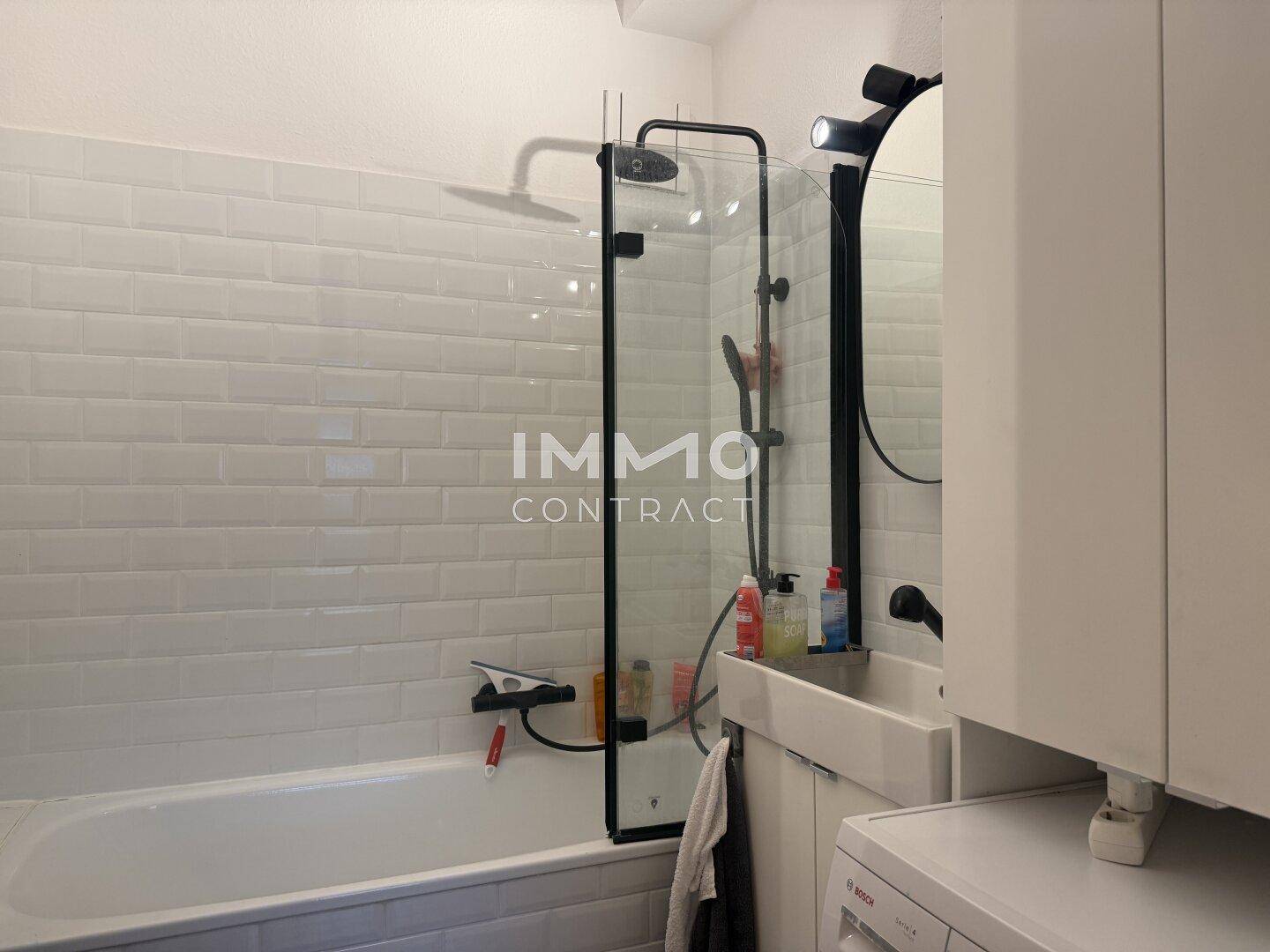 Modernes Badezimmer mit Badewanne, Dusche und weißen Fliesen.