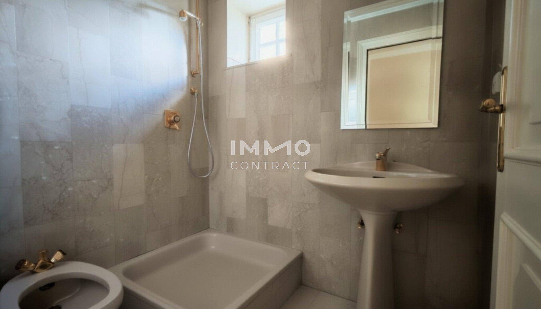 Funktionales Badezimmer mit Dusche, Waschbecken und Bidet, komplett gefliest und gut beleuchtet.