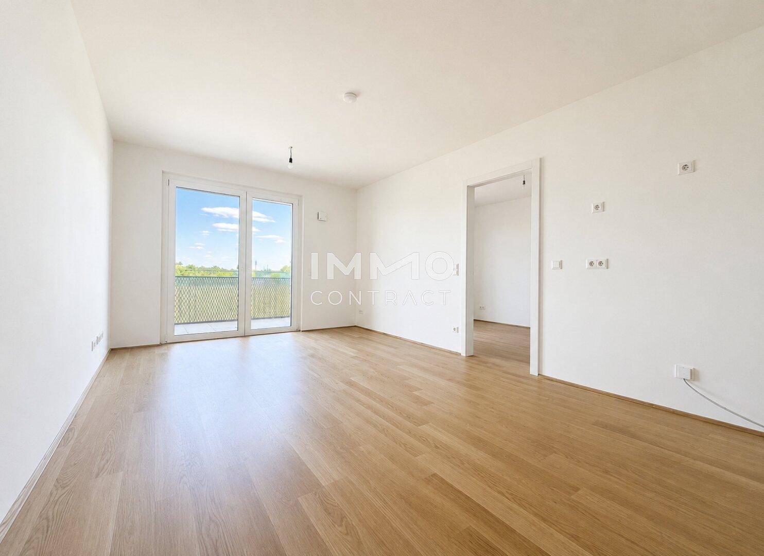 Heller, unmöblierter Wohnraum mit Eichenparkett und großzügigem Zugang zum Balkon.