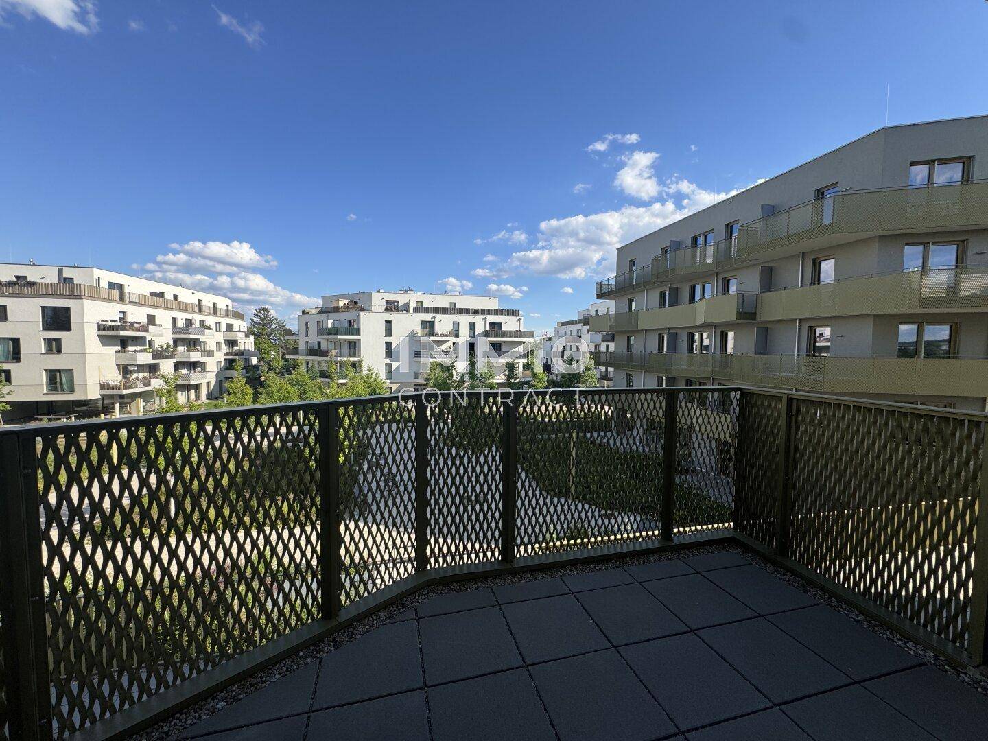 Breiter Balkon mit Metallgeländer und weitem Blick auf die moderne Wohnanlage.
