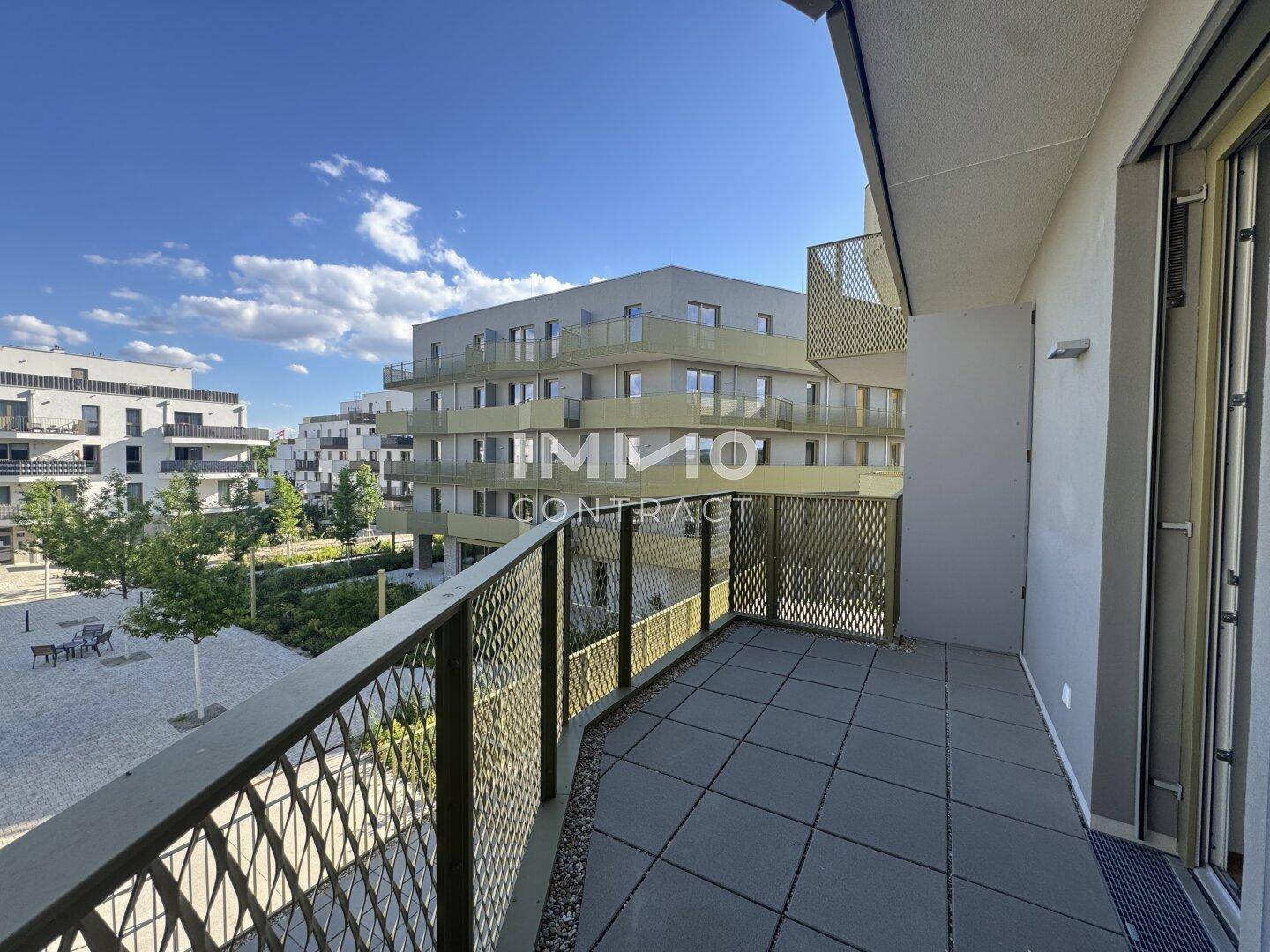 Geräumiger Balkon mit moderner Metallbrüstung und Blick auf die umliegenden Neubauten.