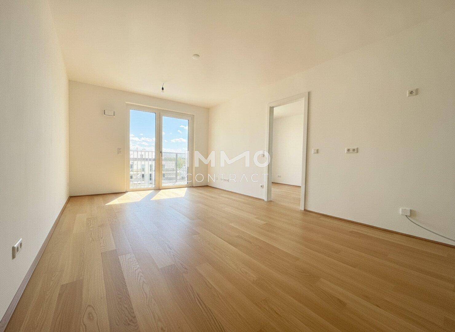 Helles, leeres Zimmer mit Holzboden und Zugang zu einem Balkon, ideal für individuelle Gestaltung.