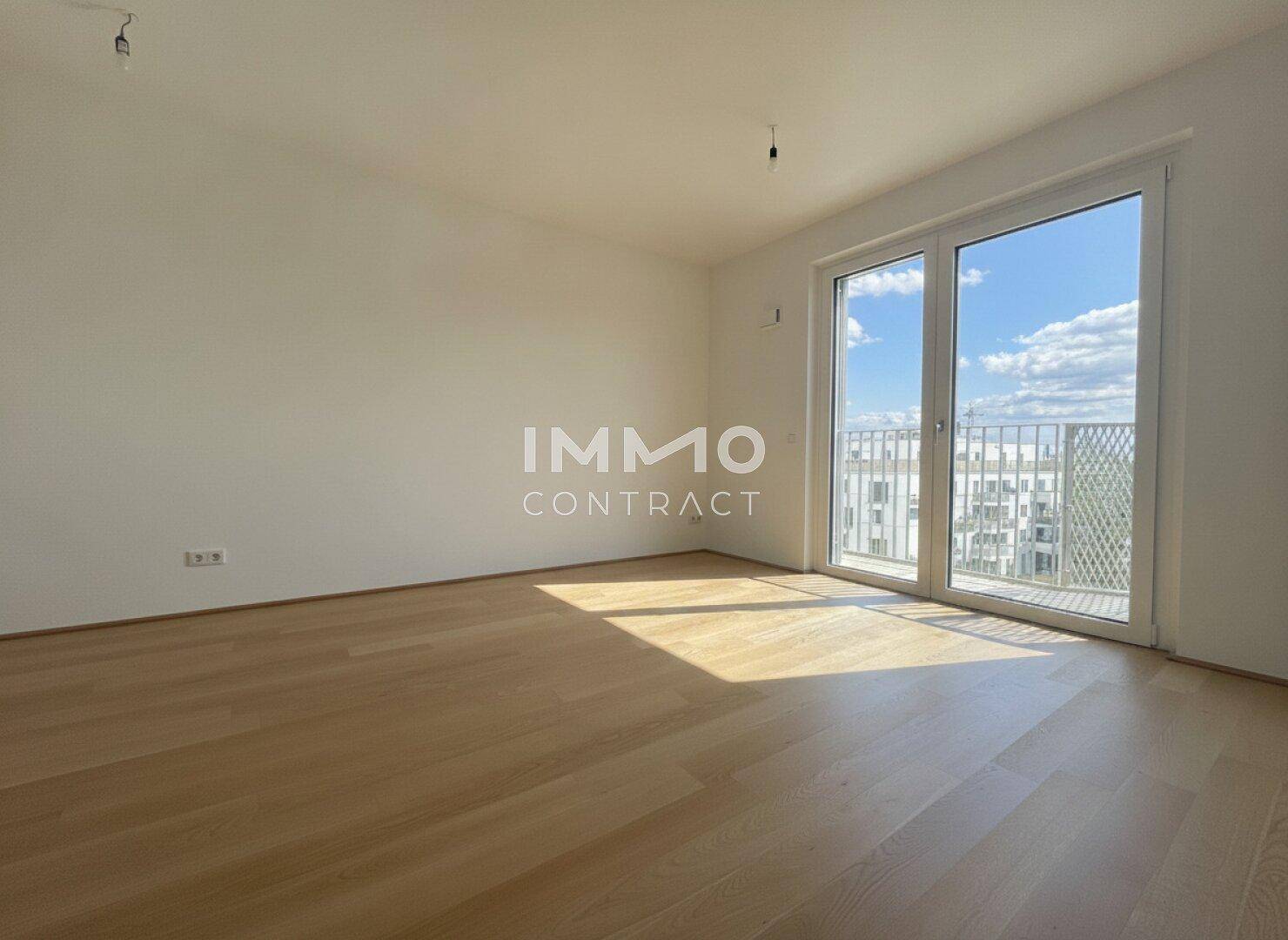 Lichtdurchflutetes Zimmer mit Holzboden und großem Fenster, das viel Tageslicht hereinlässt.