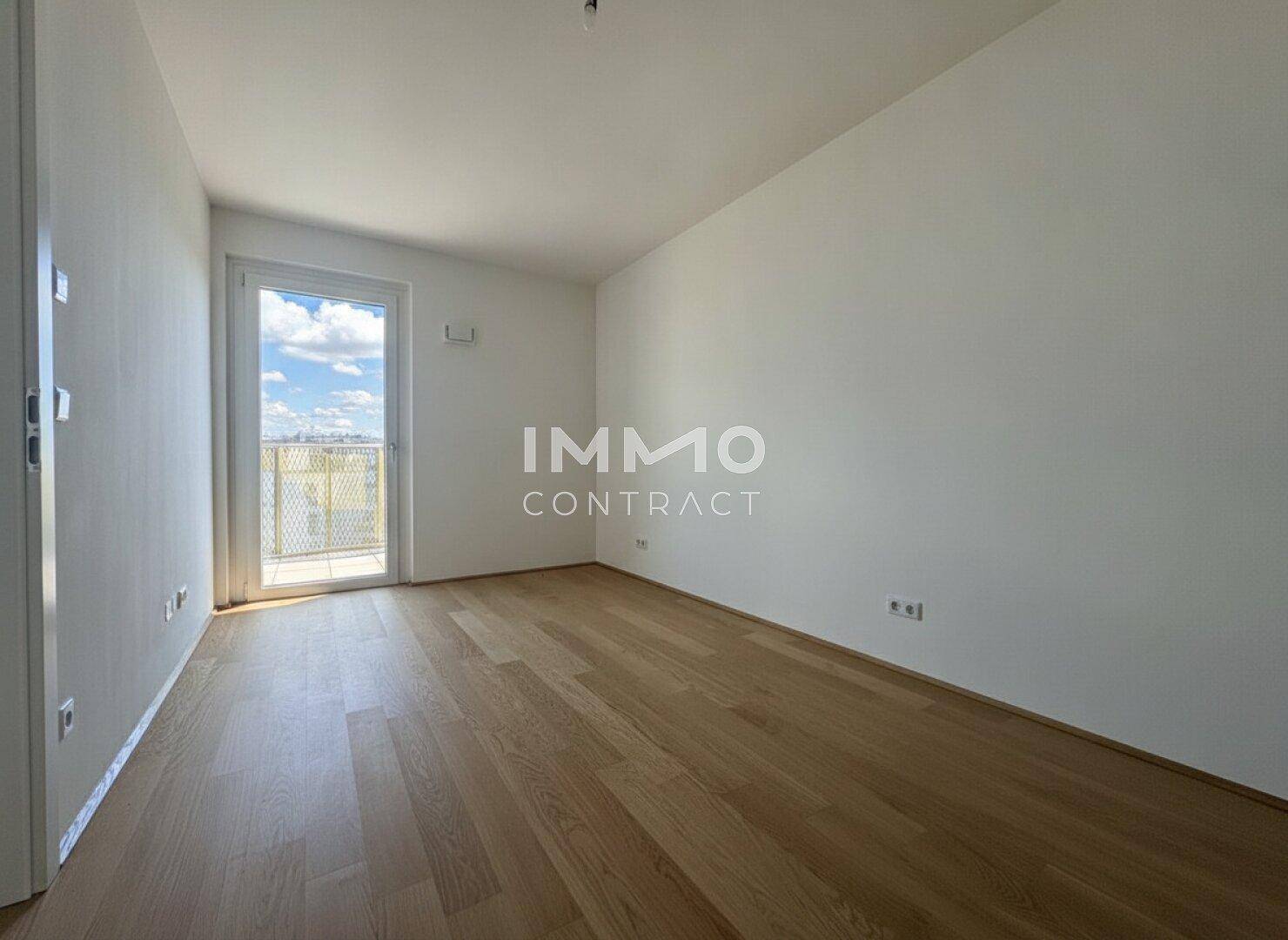 Sonniger Raum mit Holzboden und Balkonzugang, bereit für die persönliche Einrichtung.