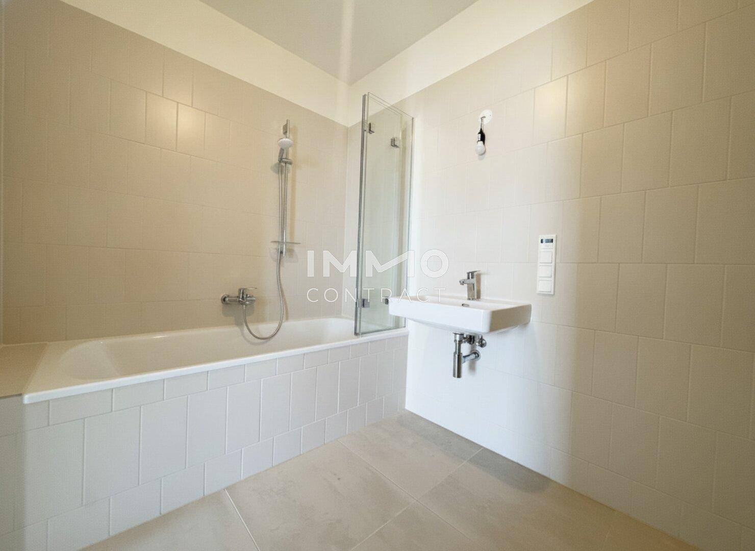 Modernes Badezimmer mit heller Fliesenverkleidung, Badewanne und einem einzelnen Waschbecken.