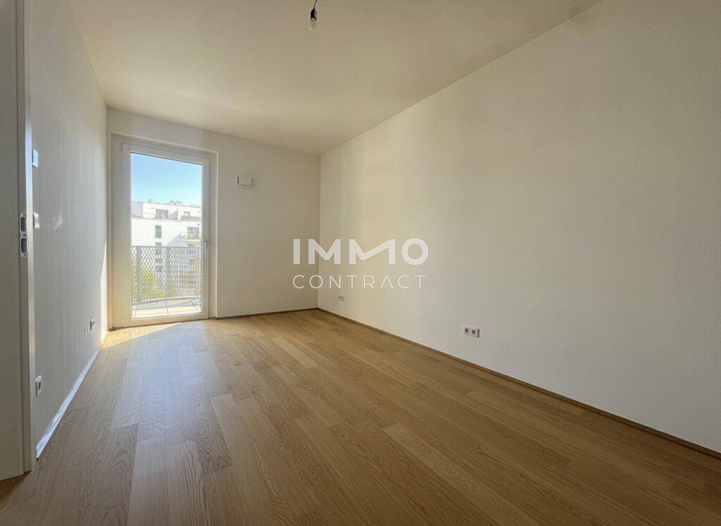 Leeres Schlafzimmer mit Holzboden und Zugang zu einem französischen Balkon, hell und modern.