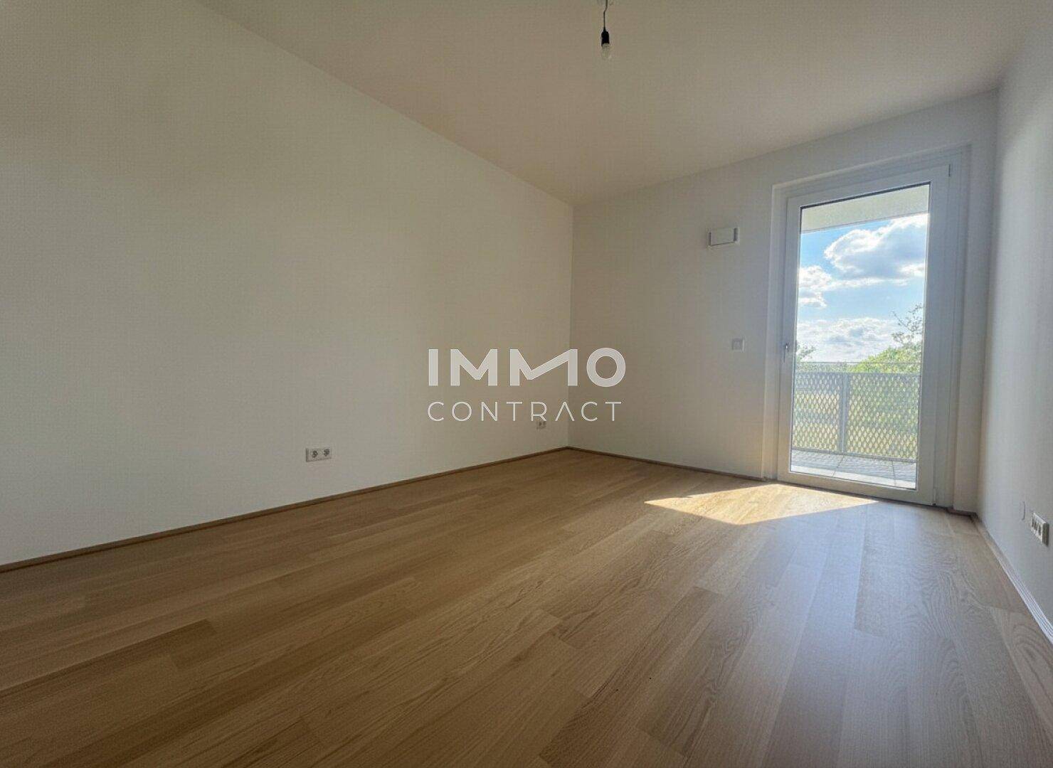Helles Schlafzimmer mit Parkettboden und direktem Zugang zum Balkon, bietet viel Tageslicht.