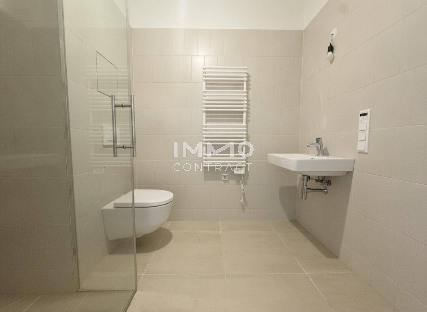 Modernes Badezimmer mit ebenerdiger Dusche, Wand-WC und beheiztem Handtuchhalter in hellen Fliesen.