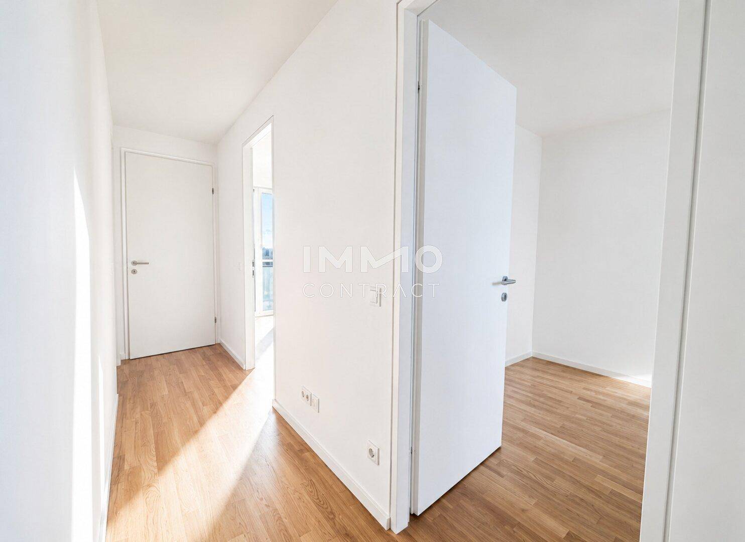 Heller Flur mit Holzfußboden, der zu verschiedenen Zimmern führt, gut beleuchtet durch Tageslicht.